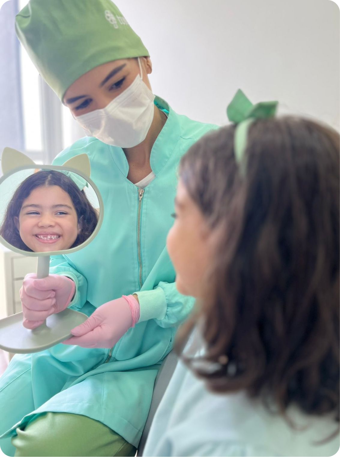 Dentista mostrando o sorriso de uma criança no espelho durante consulta
