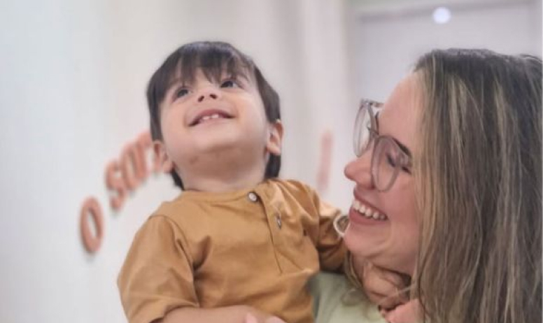 Criança sorrindo no colo durante atendimento na Turê